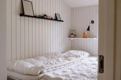 an unmade bed in a room with white walls at Bright And Lovely Summerhouse In Løkken in Løkken