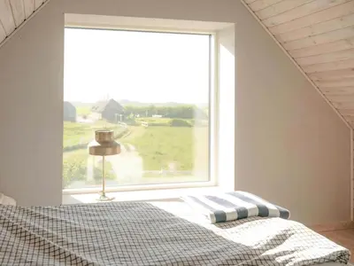 a bedroom with a bed and a large window at Renovated Farmhouse In Architectural Style in Lemvig