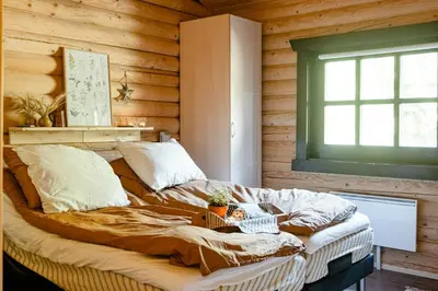 a bed in a room with a wooden wall at Authentic Log House Amid Evergreens In Vendsyssel in Fjerritslev