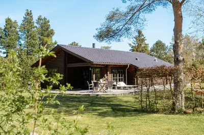 a log cabin with a patio in the yard at Authentic Log House Amid Evergreens In Vendsyssel in Fjerritslev