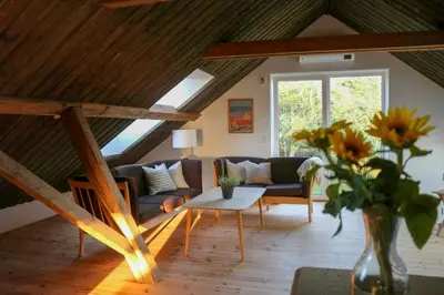 a living room with a couch and a vase of flowers at Peaceful Summer House Near Limfjorden in Nykøbing Mors