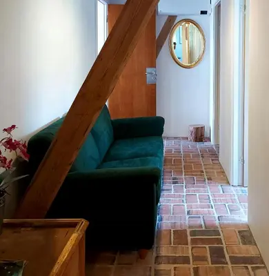 a living room with a green couch on a brick floor at Peaceful Summer House Near Limfjorden in Nykøbing Mors
