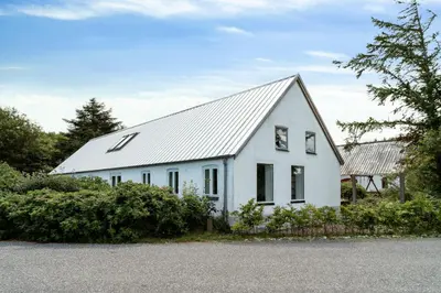 a white house with a metal roof at Renovated Estate With Private Beach in Roslev