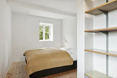 a bedroom with white walls and a bed and shelves at Renovated Estate With Private Beach in Roslev