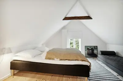 a white bedroom with a bed and a couch at Renovated Estate With Private Beach in Roslev