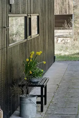 a bench next to a building with a potted plant at Authentic Friis & Moltke House In Lundo's Nature in Højslev