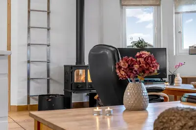 a table with a vase of flowers and a stove at Large Holiday Home With Pool And Spa In The Middle Of Blokhus Town, Close To The North Sea in Blokhus