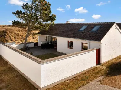 a house with a retaining wall and a tree at Charming Retreat in Rodhus - By Traum Ferienwohnungen in Pandrup
