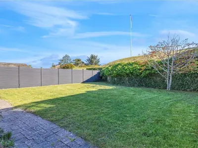 a yard with a fence and a tree at Cozy Family Retreat - By Traum Ferienwohnungen in Blokhus