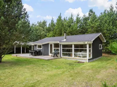 a small house with a deck and a patio at Holiday home with spacious garden in Løkken