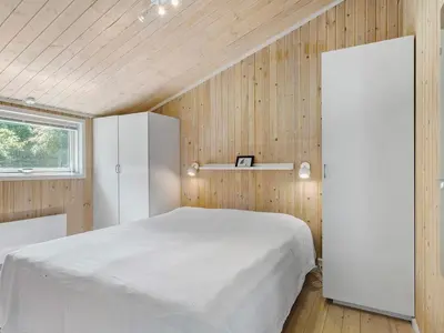 a bedroom with a white bed and wooden walls at Holiday home with spacious garden in Løkken
