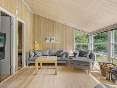 a living room with a couch and a table at Holiday home with spacious garden in Løkken