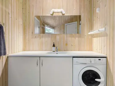 a bathroom with a washing machine and a sink at Holiday home with spacious garden in Løkken