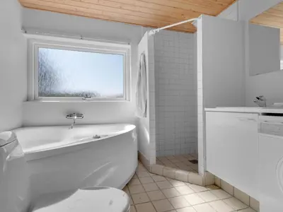 a white bathroom with a tub and a window at Green Oasis near Blokhus - By Traum Ferienwohnungen in Blokhus