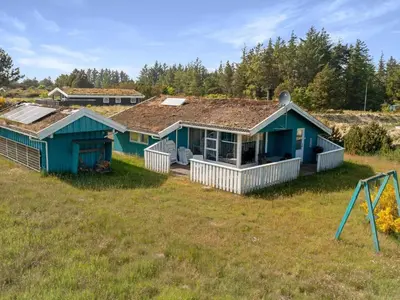 a blue house in a field with a playground at Green Oasis near Blokhus - By Traum Ferienwohnungen in Blokhus