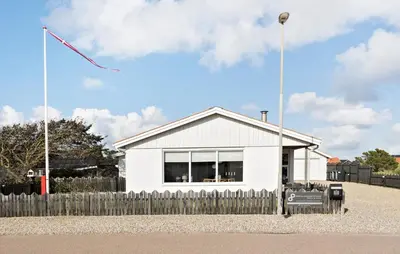 a white house with a fence and a kite in the sky at 4 Bedroom Awesome Home In Thisted in Thisted