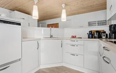 a white kitchen with white cabinets and a wooden ceiling at 4 Bedroom Awesome Home In Thisted in Thisted