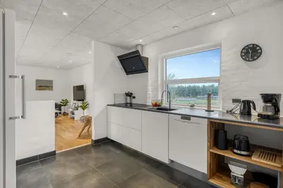 a kitchen with white cabinets and a clock on the wall at Lovely Holiday Home, Renovated In 2024, Located In Hanstholm By The North Sea in Hanstholm