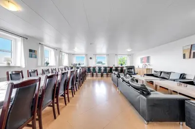a large room with chairs and tables and windows at 40-Person Holiday Home, With Large Pool Area And Panoramic Views Of The Limfjord in Thyholm