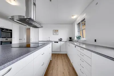 a kitchen with white cabinets and a black counter top at 40-Person Holiday Home, With Large Pool Area And Panoramic Views Of The Limfjord in Thyholm
