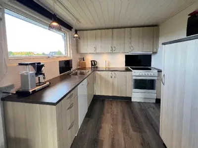 a kitchen with wooden cabinets and a large window at Hyggeligt feriehus in Thisted