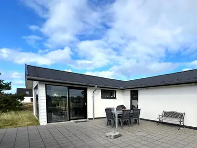 a white building with a table and chairs on a patio at Hyggeligt feriehus in Thisted