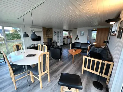 a living room and dining room with a table and chairs at Hyggeligt feriehus in Thisted