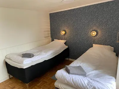 two beds in a room with two lamps on the wall at Gæstehuset Husly in Haderup