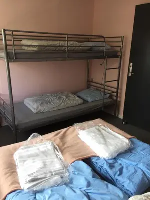 two bunk beds in a room with blue sheets at Hostel Agger Vandrerhjem in Agger