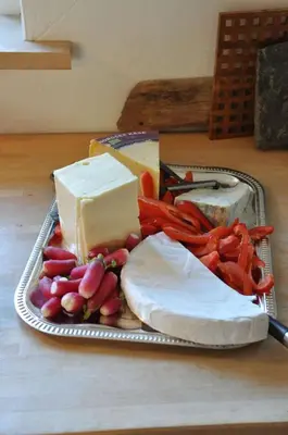 a tray of cheese and vegetables on a table at Hostel Agger Vandrerhjem in Agger