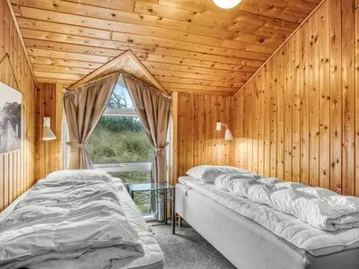 two beds in a wooden room with a window at Holiday Home Annemone - 600m from the sea by Interhome in Torsted