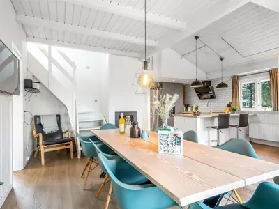 a dining room and kitchen with a wooden table and chairs at Holiday Home Caya - 750m from the sea by Interhome in Løkken