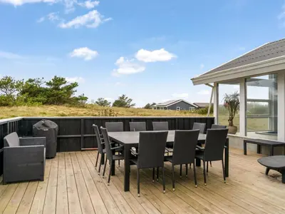 a patio with a table and chairs on a deck at Holiday Home Caya - 750m from the sea by Interhome in Løkken