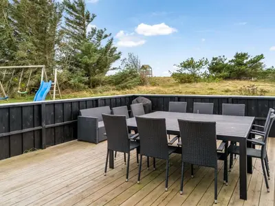 a table and chairs on a deck with a playground at Holiday Home Caya - 750m from the sea by Interhome in Løkken