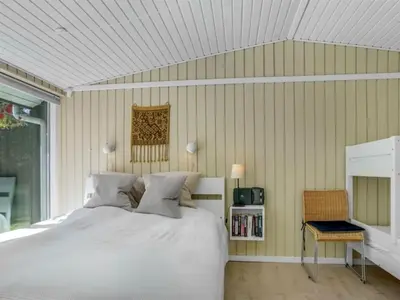 a bedroom with a white bed and a television at Holiday Home Quiana - 2km from the sea by Interhome in Pandrup