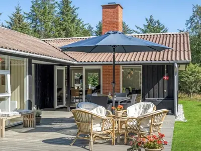 a patio with a table and chairs and an umbrella at Holiday Home Quiana - 2km from the sea by Interhome in Pandrup