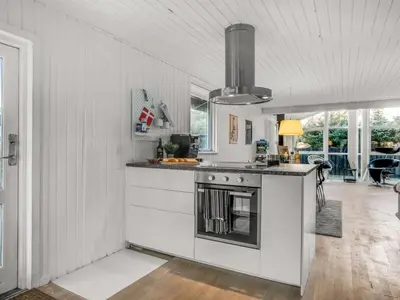 a kitchen with white cabinets and a stove top oven at Holiday Home Baldo - 800m from the sea by Interhome in Blokhus