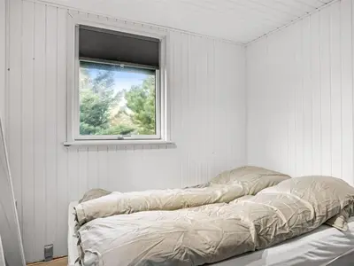 a bed in a white room with a window at Holiday Home Baldo - 800m from the sea by Interhome in Blokhus