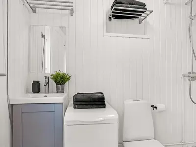 a white bathroom with a toilet and a sink at Holiday Home Baldo - 800m from the sea by Interhome in Blokhus