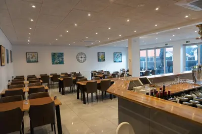 a restaurant with tables and chairs and a bar at Birkelse Hotel og Kro in Birkelse