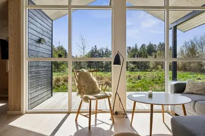 a living room with a large window and a table at Modern Holiday Home From 2017, Located At Lild Strand in Frøstrup
