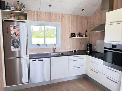 a kitchen with white cabinets and a stainless steel refrigerator at Modern Holiday Home From 2017, Located At Lild Strand in Frøstrup