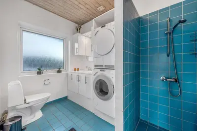 a bathroom with a toilet and a washing machine at Lovely Holiday Home With Pool, Spa And Sauna, Only 200 Meters From The North Sea in Harboør