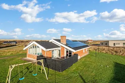 a house with a solar roof and a playground at Lovely Holiday Home With Pool, Spa And Sauna, Only 200 Meters From The North Sea in Harboør