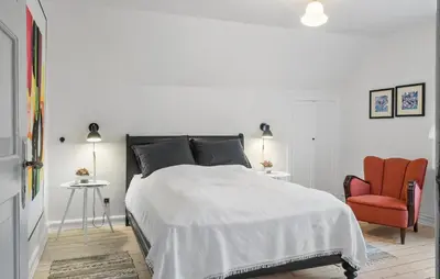 a white bedroom with a bed and a red chair at Cozy Home In Thyborøn With Wifi in Thyborøn