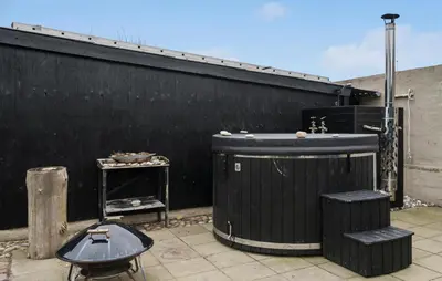 a patio with two trash cans and a black wall at Cozy Home In Thyborøn With Wifi in Thyborøn