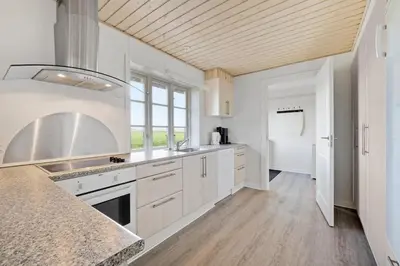 a kitchen with white cabinets and a counter top at Jørgen's Feriehus in Lemvig