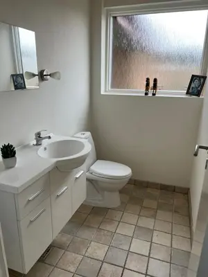 a bathroom with a toilet and a sink and a window at Dejlig og hyggelig hus i Thyborøn in Thyborøn