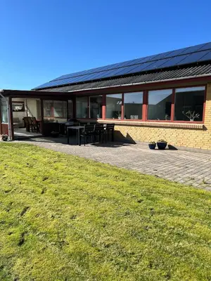 a building with a black roof and a grass field at Dejlig og hyggelig hus i Thyborøn in Thyborøn