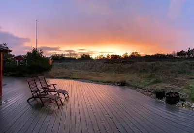 two benches sitting on a wooden deck at sunset at Vesterhavsluft Og Natur Ved Nationalpark Thy in Thisted